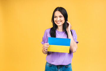 Fototapeta premium Portrait of nice beautiful lovely glad cheerful woman holding in hands Ukrainian flag having fun isolated over yellow pastel color background.