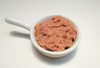 Refried beans (Phaseolus vulgaris)  in a white bowl, Mexican dish.
