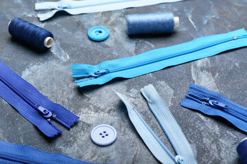 Stylish blue zippers, threads and buttons on blue grunge background