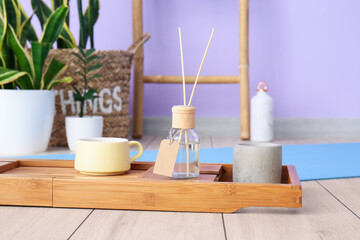 Tray with cup, reed diffuser and candle in room, closeup