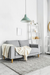 Grey sofa with plaid and shelving unit in light living room