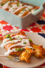 Cheese enchiladas in a casserole dish on a festive Mexican fabric background