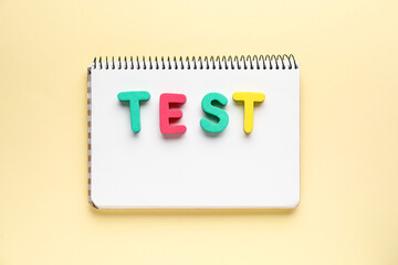Notebook with word TEST on beige background