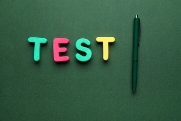 Word TEST with pen on green background