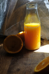 Orange juice bottle on a wooden table with squeezed orange