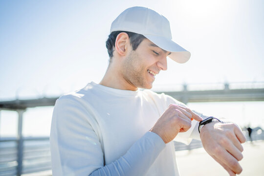 Uses smart pulse and cardio watches, male athlete running outside active training in sportswear