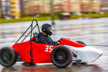 An adult rides a racing car on an empty wet rainy road or track at high speed - motion blur. Training men to drive a racing car. Racing school. © Евгений Панов