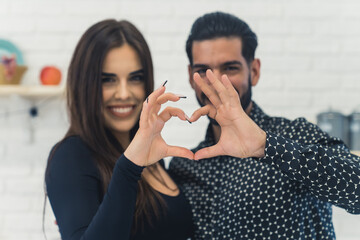 A lovely cute couple making a heart gesture to the camera. High quality photo