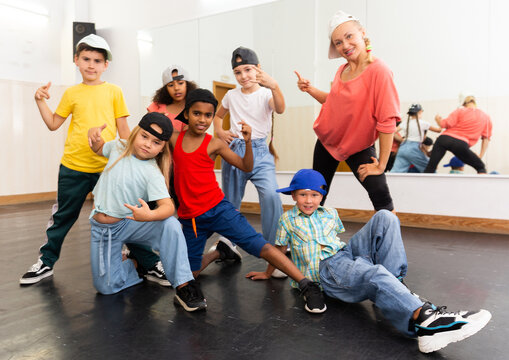 Portrait of happy girls and boys hip hop dancers and woman instructor posing during group dance workout