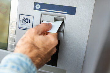 Male hand inserting ATM card into ATM bank machine