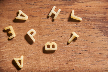 Letters of the alphabet word made of soup pasta placed in disorder on wood