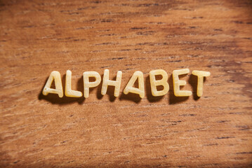 Word Alphabet formed with pasta letters on a wooden background.