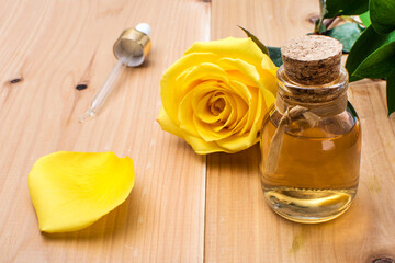 glass bottle of essential oil with yellow rose and pipette