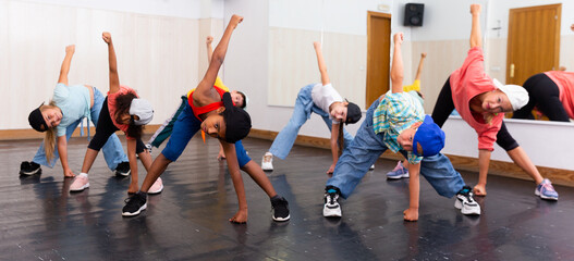 Group of children in casual clothes training hip-hop in class, learning modern dance movements