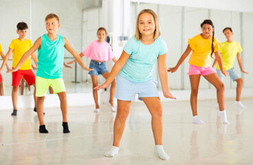 Fototapeta premium Portrait of cheerful preteen girl learning dynamic Charleston in choreographic studio for children.