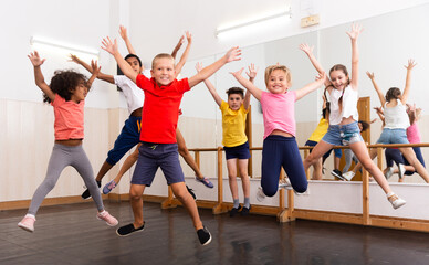 Fototapeta na wymiar Group of cheerful children dancing and jumping in dance studio during class