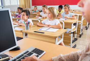 Multiracial group of kids working at class, watching presentation in classroom