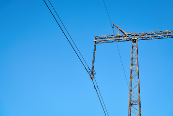 High voltage electricity tower with power line against blue sky. Overhead electric power line with insulators. Electricity generation, transmission, and distribution network. Indastry landscape.