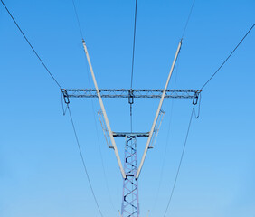 High voltage electricity tower with power line against blue sky. Overhead electric power line with...