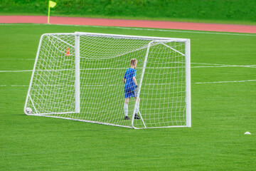 Young goalkeeper stands by the soccer gate.