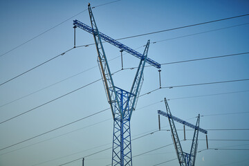 High voltage electricity tower with power line against blue sky. Overhead electric power line with...