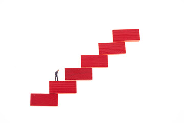 Career ladder concept.Career growth. Figurine of a businessman on a red step ladder isolated on a...