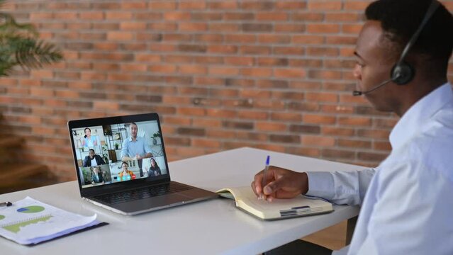 Online business meeting of multiracial group. Successful african american man looking at computer screen, talking on video link, talking strategy and workplan, discussing project,plans company future 