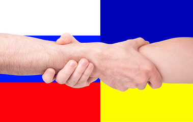 Two men's hands clasping each other in a firm grip that looked like a handshake against the background of the flags of Russia and Ukraine