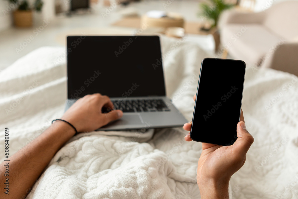 Poster pov of man using smartphone and laptop in bedroom, cropped