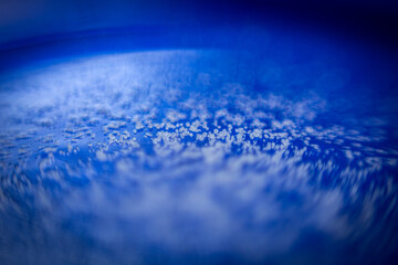 Micro closeup focus of grains of salt or sugar on blue surface