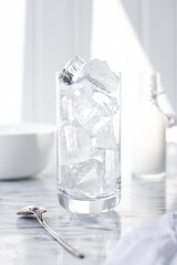 Glass being filled with clear ice by woman