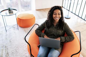 Portrait of smiling black woman using laptop at home - obrazy, fototapety, plakaty