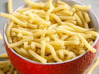 Closeup of Italian food yellow raw uncooked vermicelli, macaroni, noodle, pastry, pasta on the isolated bowl (close-up,meal, cuisine, cooking, gray, dry, dish, studio, plate,dinner, tile, cement)