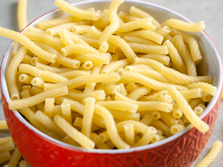 Closeup of Italian food yellow raw uncooked vermicelli, macaroni, noodle, pastry, pasta on the isolated bowl (close-up,meal, cuisine, cooking, gray, dry, dish, studio, plate,dinner, tile, cement)