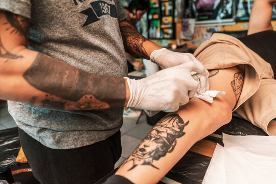 Latin tattooist sterilizing the leg of a client to proceed to capture an art in Managua, Nicaragua