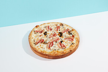 Italian pizza with mushroom and bacon on coloured background. Mushroom pizza with bacon in minimal style on blue and orange color. American pizza delivery concept with color backdrop