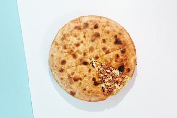 Closed pizza with minced meat, potatoes and cheese on coloured background. Meat pie with potatoes and cheese in minimal style. American pizza delivery concept with color backdrop.