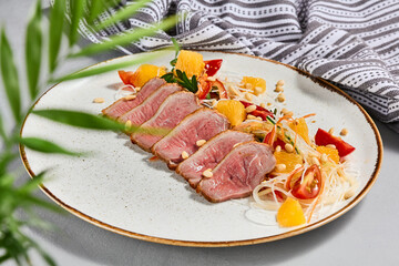 Healthy salad with duck meat, orange and vegetables. Chinese food - duck salad with citrus and fresh dressing. Sliced duck meat with crispy vegetables and pine nuts.