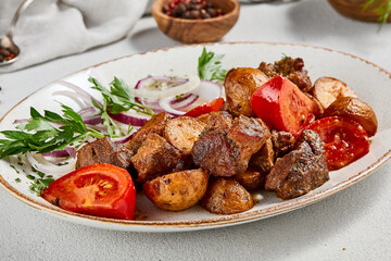 Traditional georgian dish odjahuri with meat and potatoes. Roasted pork fillet and potatoes with onion and tomatoes. Stew meat and potatoes. Eastern food with pork and spices
