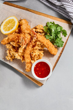 Traditional asian appetizer - crispy shrimps with sauce. Tempura shrimps on wooden board. Prawn tempura in panko breaded with spicy sauce. Pan asian food. Summer menu.