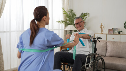 asian handicapped mature male doing resistance exercise on wheelchair with his nursing aide. they...