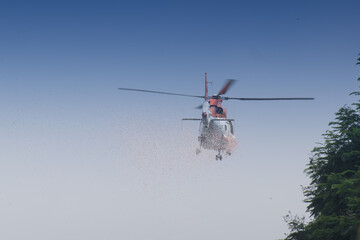 Fototapeta na wymiar KOLKATA, WEST BENGAL / INDIA - AUGUST 15TH, 2016 : A helicopter throwing flowers in air, under blue sky for celebration of India's Independence, on Independence day.