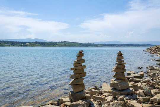 Rock cairn the art of stone balancing on a stone near a blue water flowing lake. Sunny day on the lake. A mood of calm and harmony with nature.
