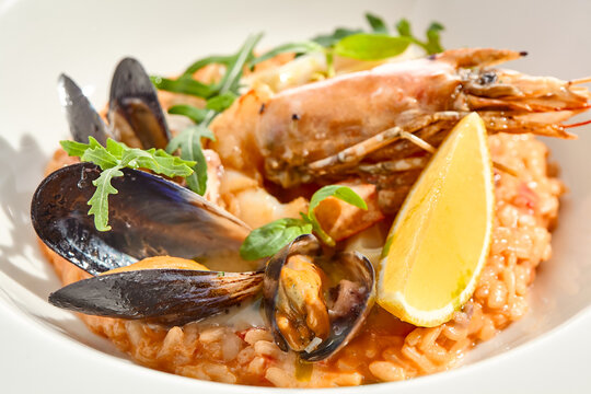 Italian dish - seafood risotto on white plate. Risotto frutti di mare with shrimp, mussels and squid. Seafood in marinara sauce with arborio rice. Paella with prawn and mussels. Seafood menu.