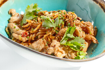 Japanese soba with chicken cooked on wok in asian style on white background. Noodle with chicken in ceramic bowl. Indonesian wok with soba noodles. Spicy thai dish with meat and udon.