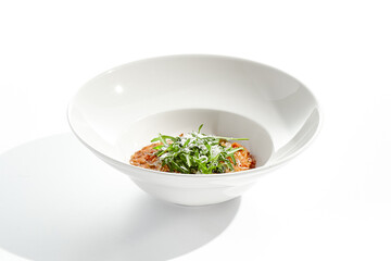 Vegan tomato risotto with rucola on white plate. Italian dish - veggie risotto isolated on white background. Plant based dining. Clean eating in restaurant menu. Eat less meat. Vegetarian lunch.