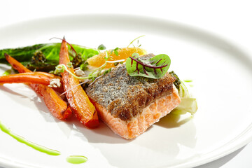 Healthy food - salmon fillet with roasted chinese cabbage and carrot. Clean eating - trout with garnish from vegetables and cream cheese and caviar. Fish steak and vegetables on white plate.