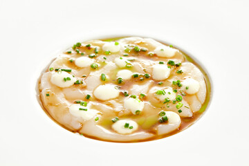Delicious food - sea scallop carpaccio in yuzu sauce on white background. Scallop ceviche in japanese style. Scallop crudo in citrus sauce and creamy espuma. Delicacy seafood in restaurant menu.