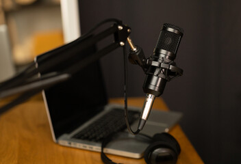Fototapeta na wymiar Desk of host streaming radio podcast at home broadcast studio.Such as laptop condenser microphone and headphone on table. Recording host streaming radio podcast interview conversation at home