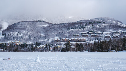 View on a snowman and the frozen Lake Tremblant on a cold winter day, near Tremblant ski resort in Quebec, Canada